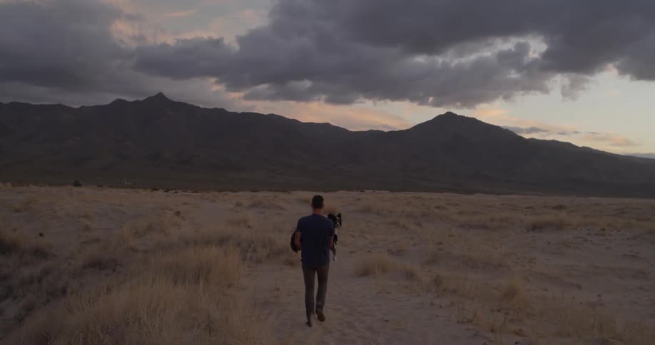 A man carries a dog through a field