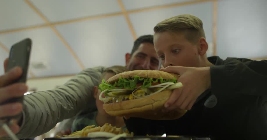 A man films his child eating a super huge burger