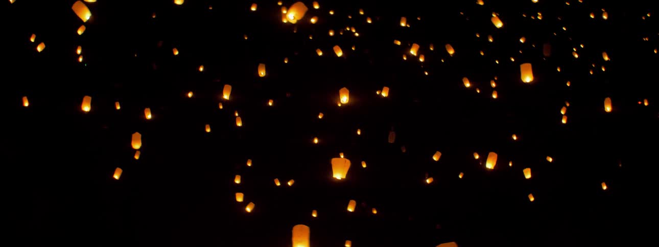 Glowing lanterns float into the night sky