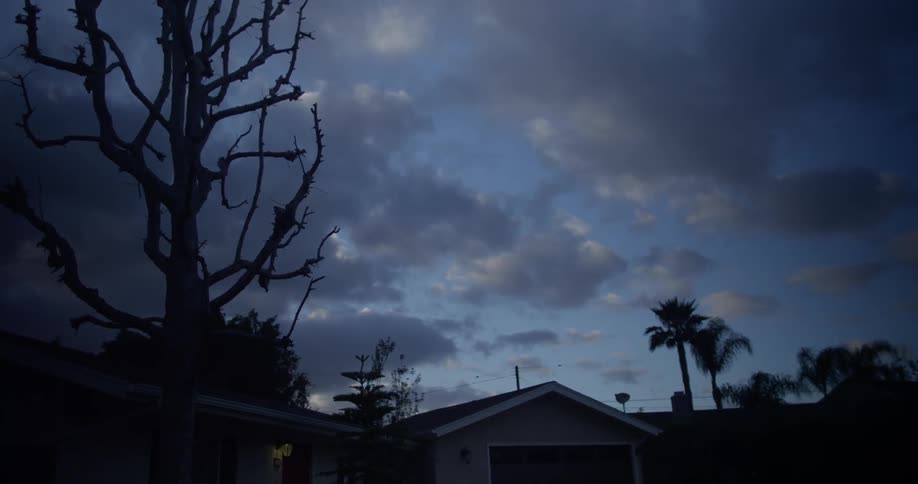 Clouds float over a house at dusk