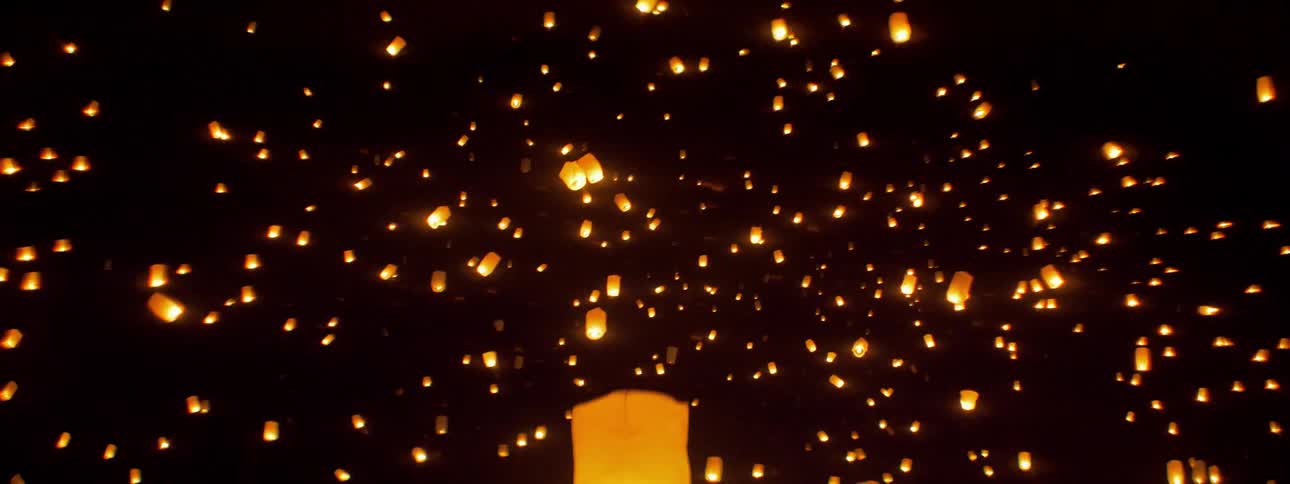 Hundreds of paper lanterns float upwards into the night sky