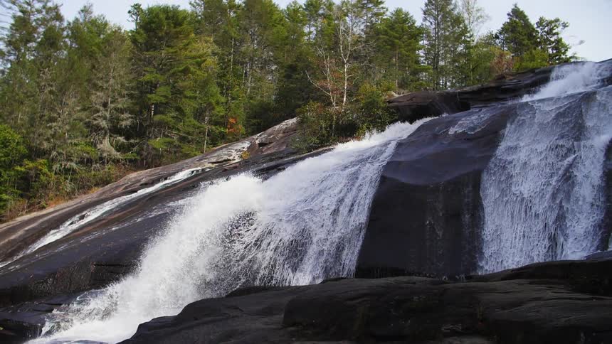 The waterfall is wide with trees at the top