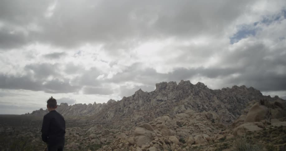 A boy throws a rock at a mountain