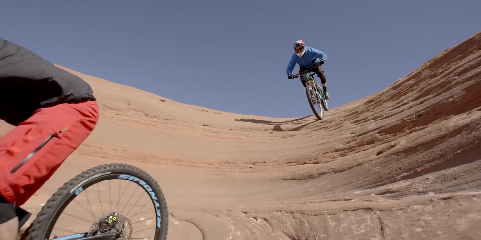 Two men ride bikes down into a cavern