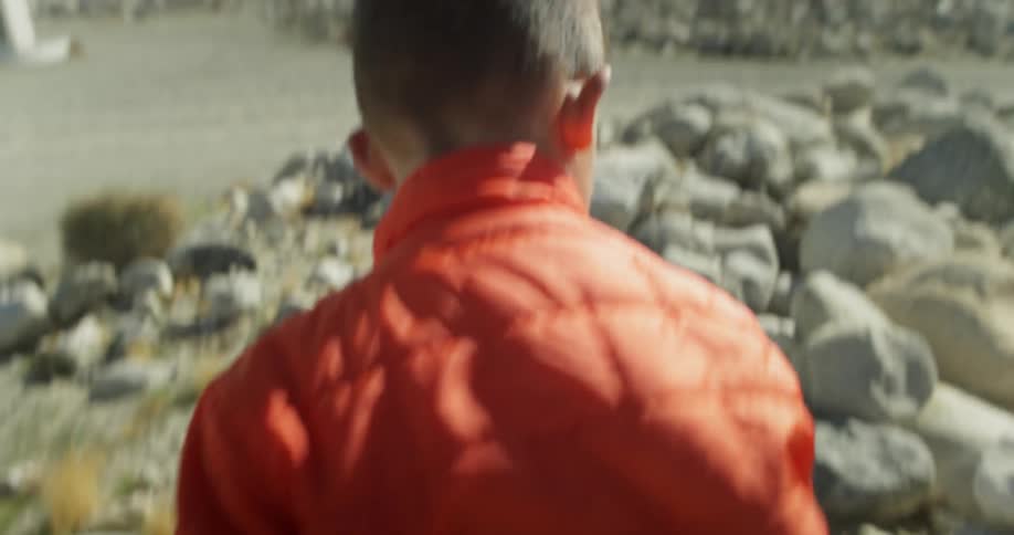 Child walks over rocks and picks one up
