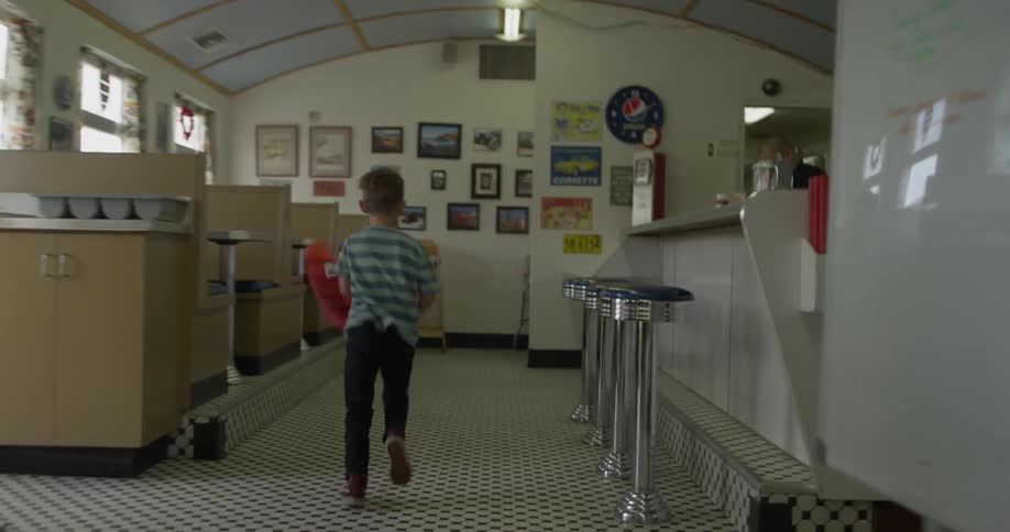 A boy runs through a diner