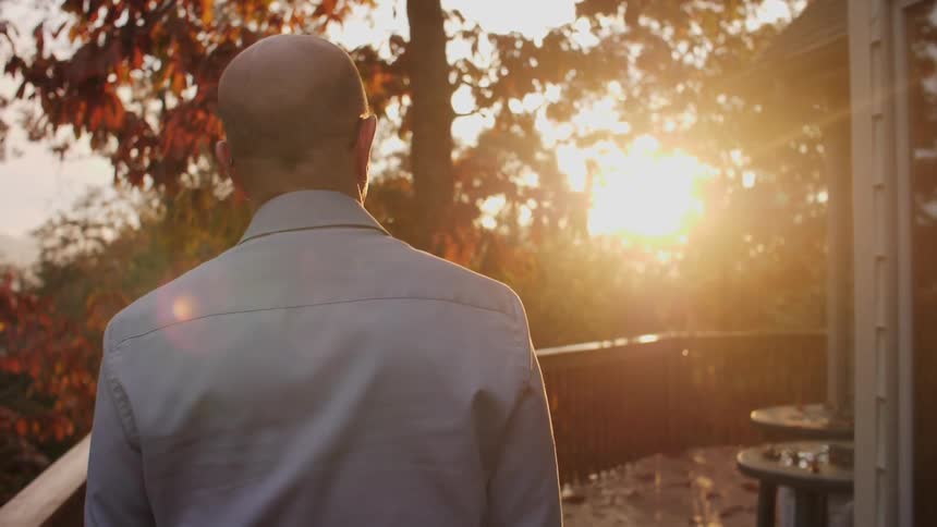 A man walks on a deck at sunset