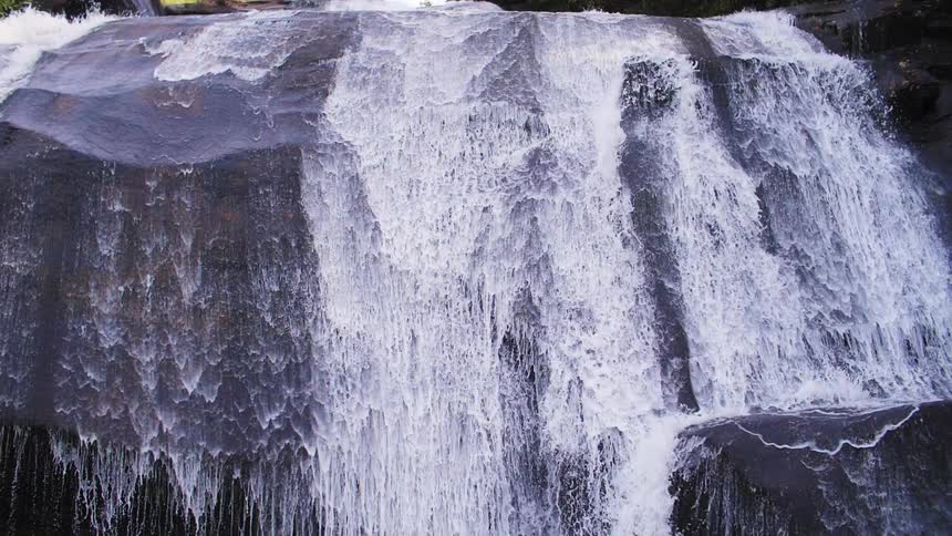 A river cascades and flows over a sheer precipice and ledge during the day