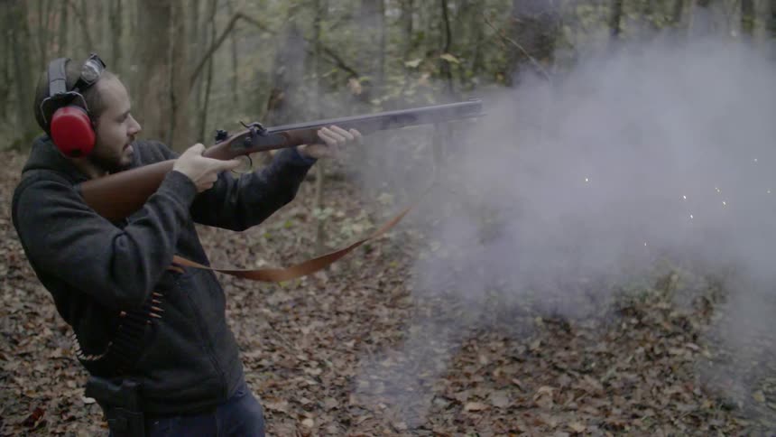 A man shoots a rifle in the woods