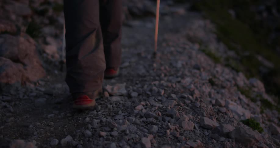Person using walking sticks to hike over rocks