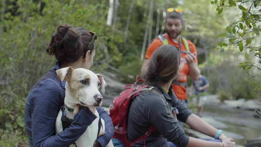 A man, women and a dog rest on a hiking trip