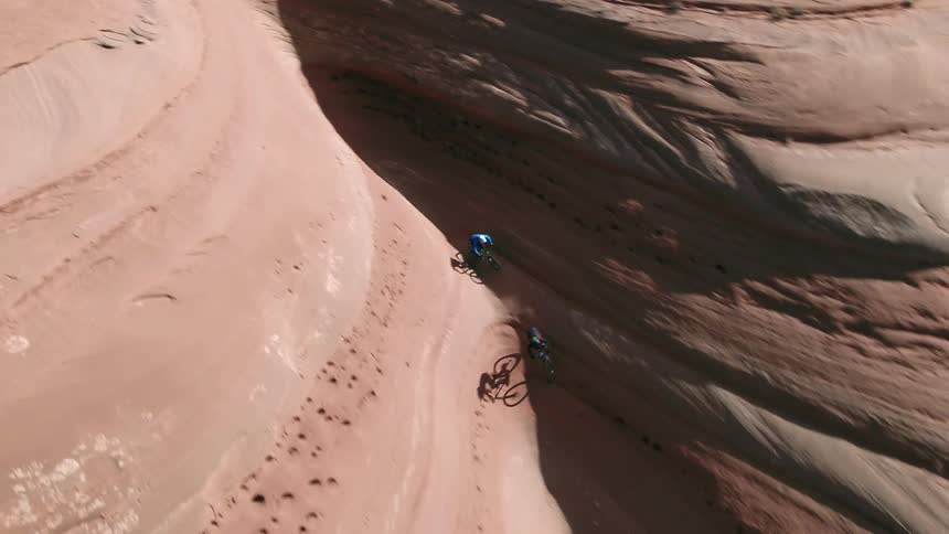 Two people ride bikes down into a cavern