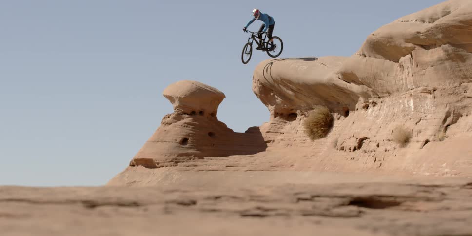 A man jumps his bicycle off a cliff