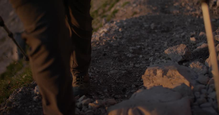 A man hikes up a gravelly path
