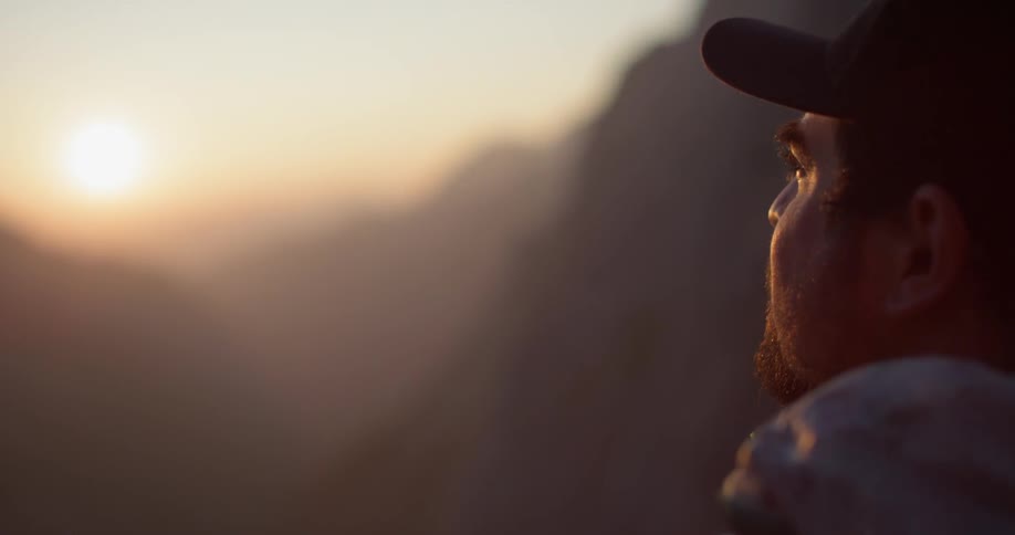 A man stares out towards the sunset