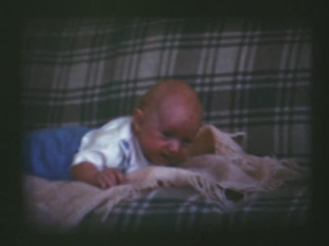 An infant fidgets while laying on a couch