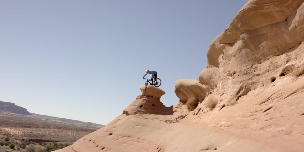 A bicyclist jumps on rock formations in the desert