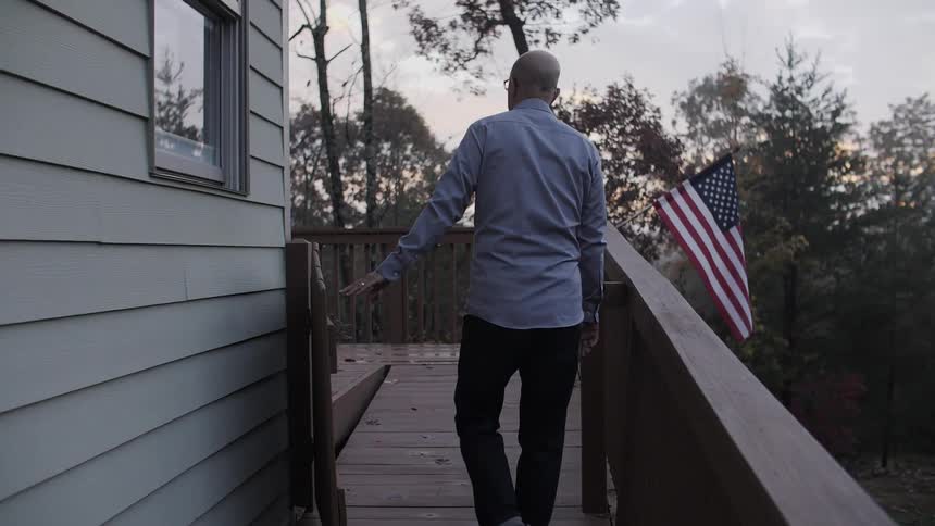 Man standing on a balcony opens a gate