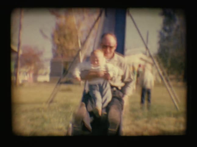 A man slides down a slide with a baby in his arms
