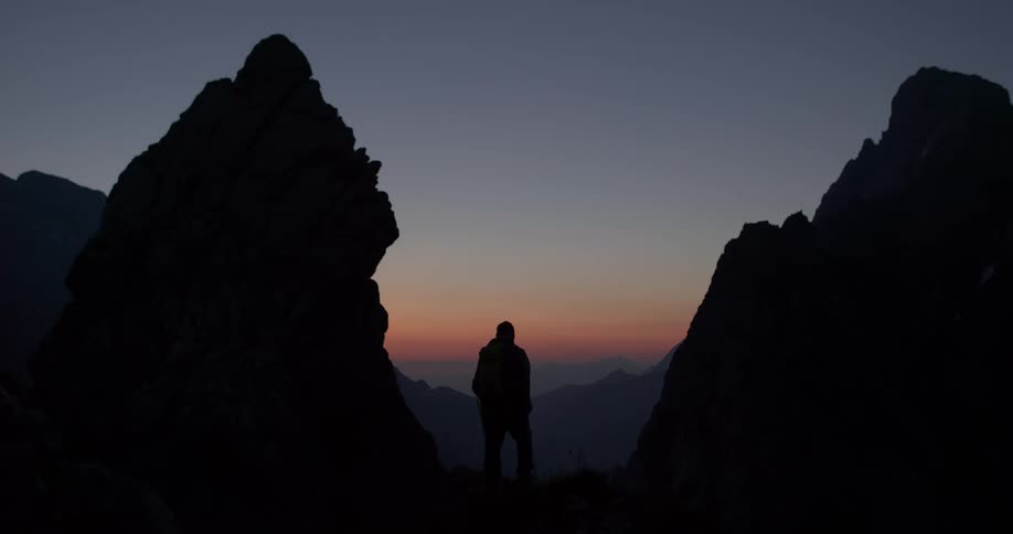 A man hikes in the mountains at dusk
