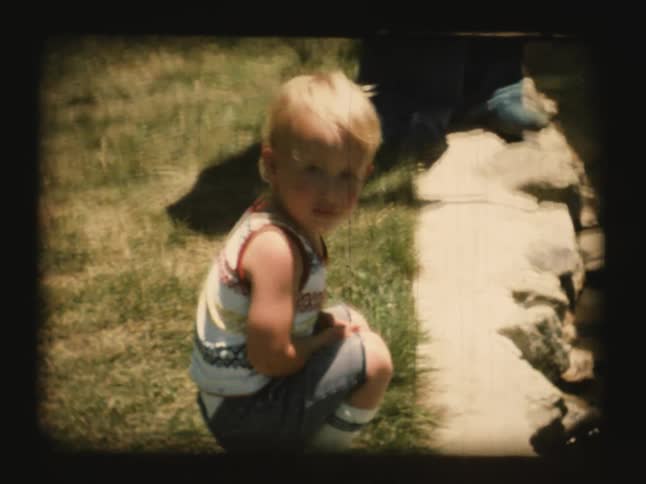 A young child leans down next to a ledge