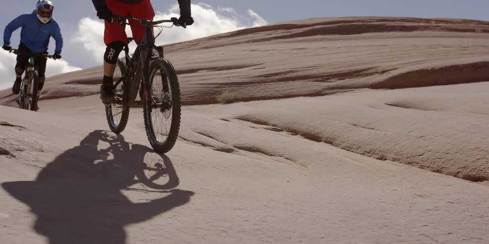 Bicyclists ride on a rock formation in the desert