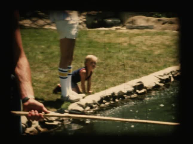 People stand around a pond fishing