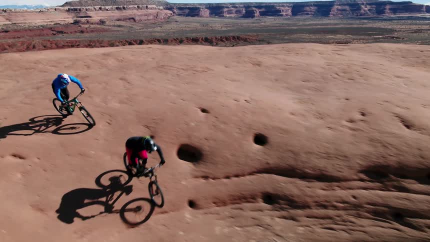 Two people ride bikes down into a cavern