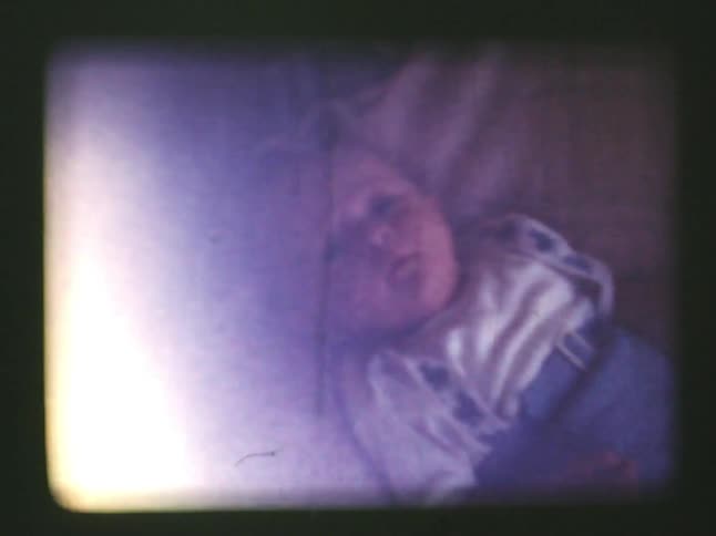 A baby lays on a blanket draped on a couch