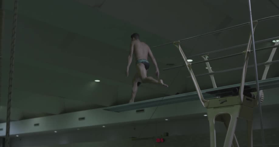 A diver jumps and performs a dive into a pool