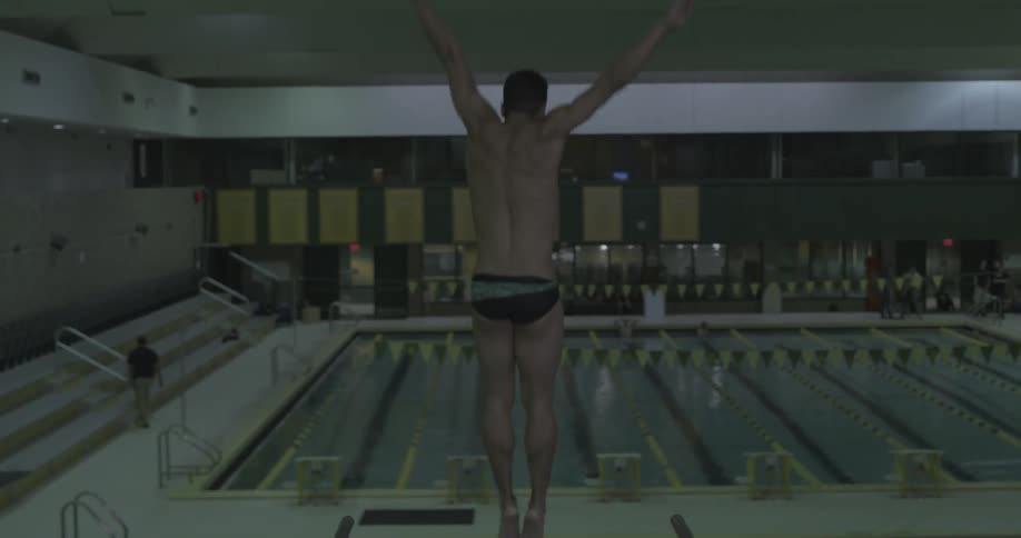 A man dives off the board into the pool