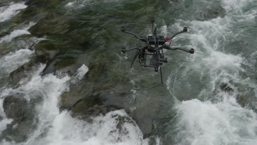 A drone flies over a river rapids