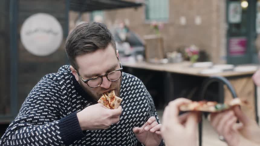 A group of people dine on pizza at an outdoor table