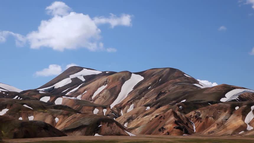 Patches of snow cling to a mountainside on a sunny day