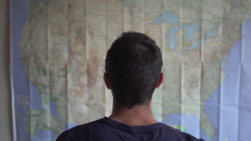 A man stares at a map hanging on the wall