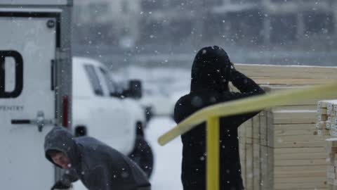 People grab boards of wood as it snows