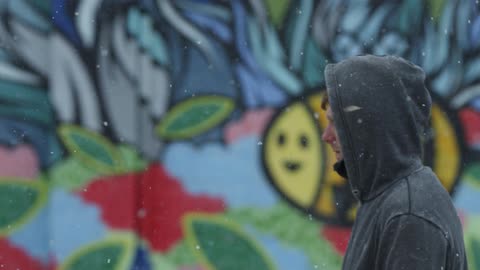 A man walks outside as it snows