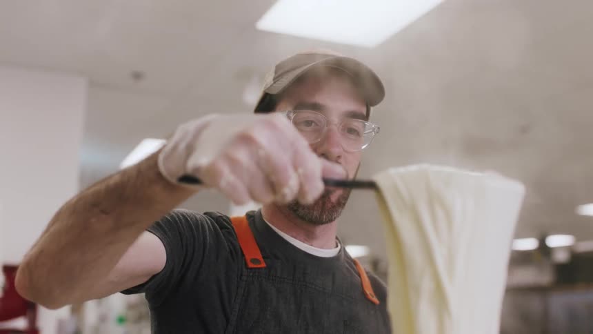 A man is pulling dough out of a steaming pot