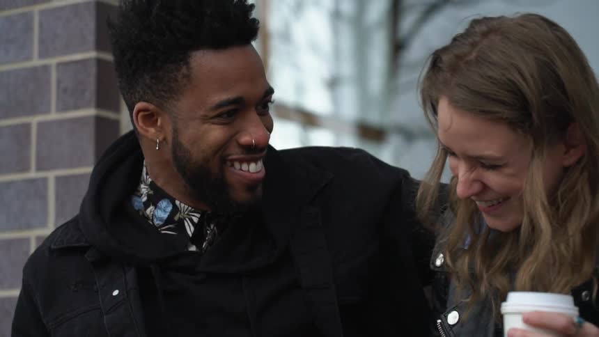 A couple are laughing together outdoors
