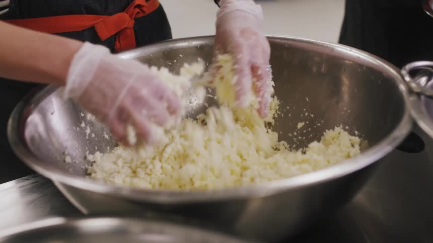 Chefs mix up food in large steel bowls