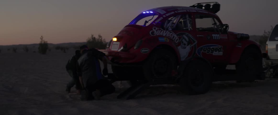 A man crawls under a vehicle