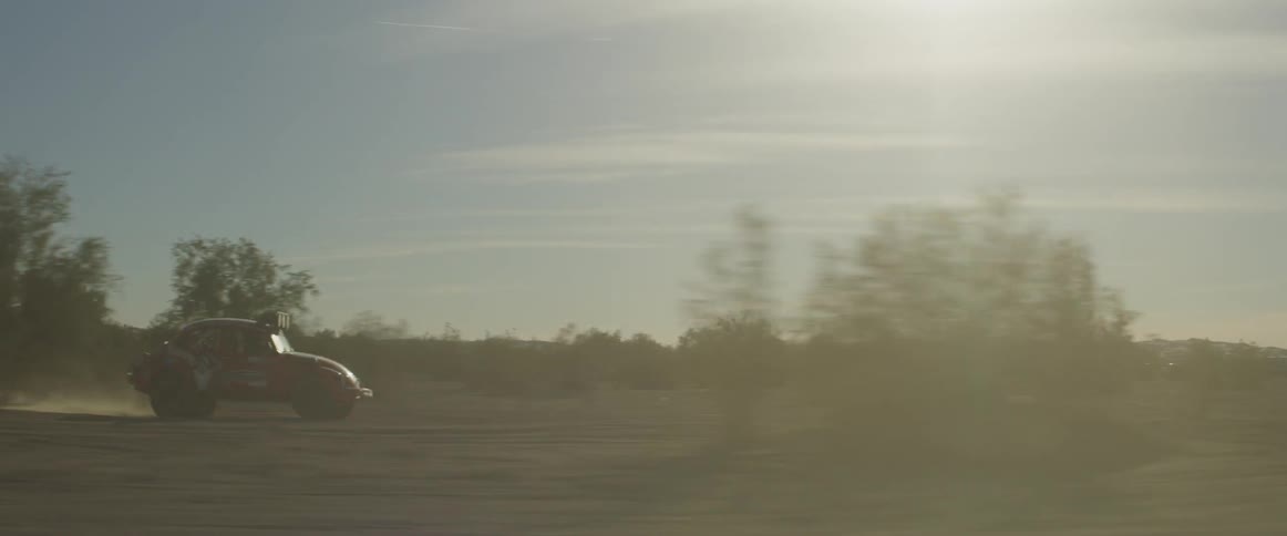 A rally car drives through the desert