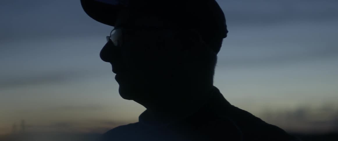 A man stands outside at dusk