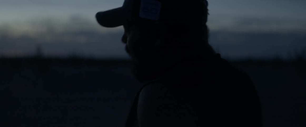 Bearded man wearing a cap outdoors at sunset
