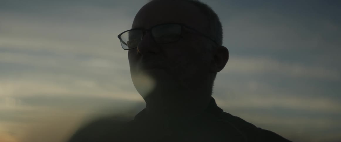 A man stands outside at dusk