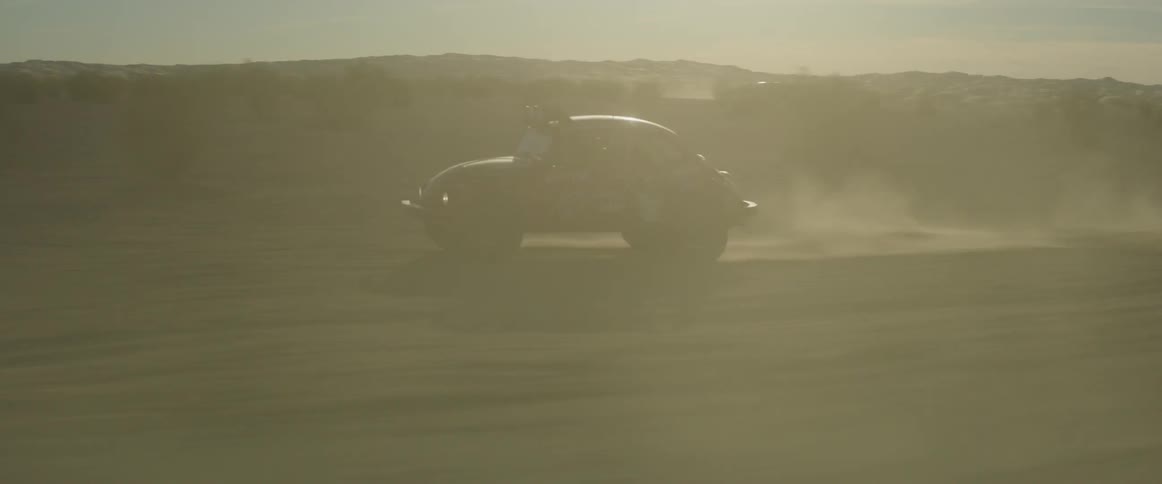 A vehicle races in the foggy desert