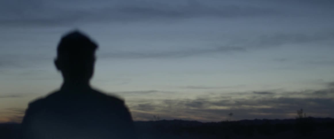 A man stands outside at dusk