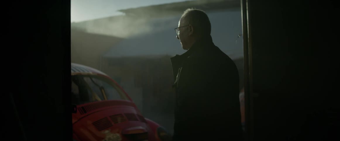 A man in glasses steps outside  from the garage