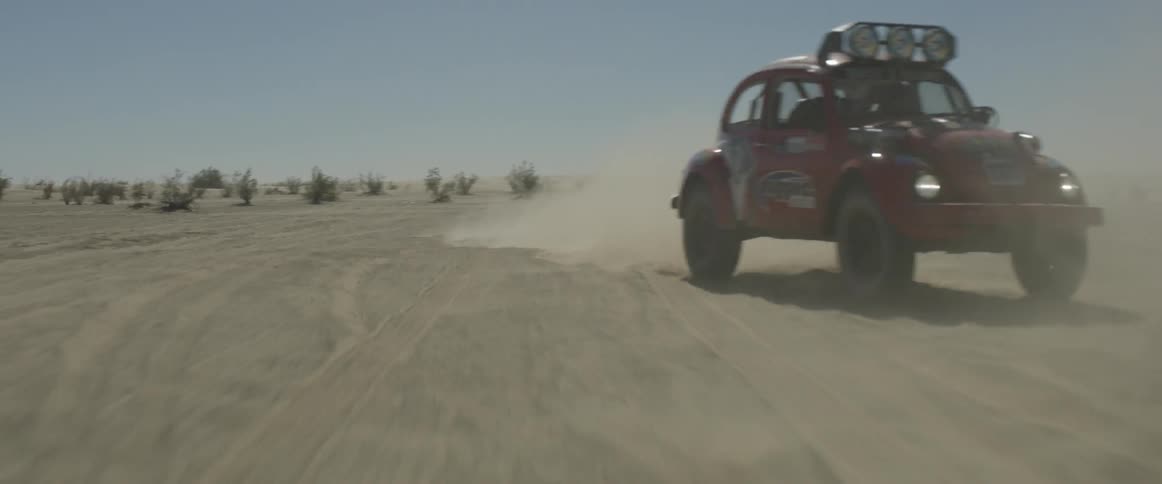 A car is off roading in the desert kicking up dust