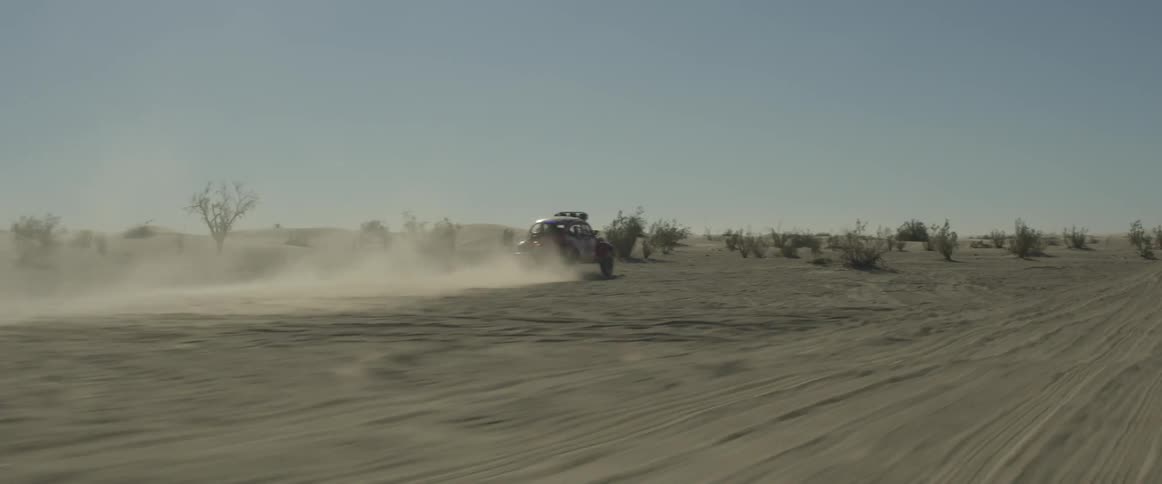 A rally car drives through the desert